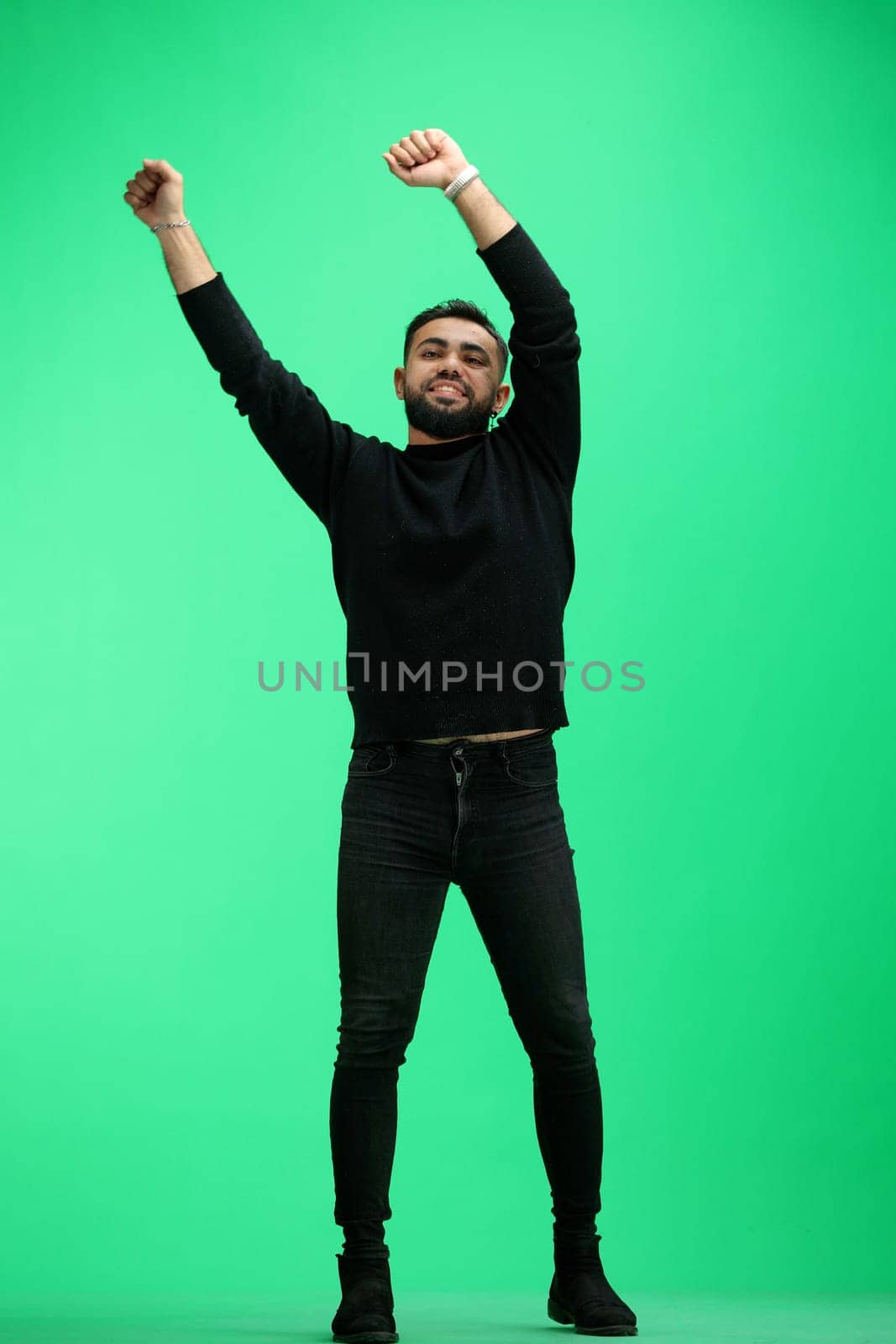 A man, full-length, on a green background, waving his arms.