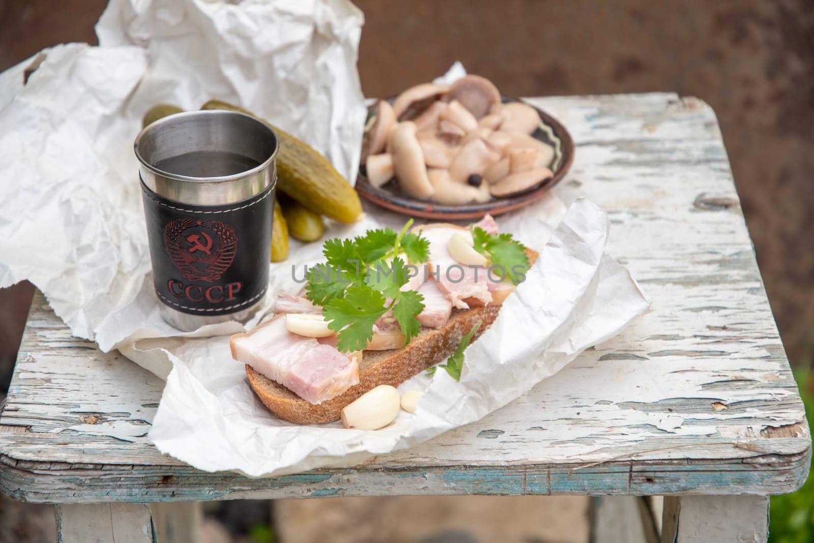 Lard with black bread, pickled cucumber for a snack and a glass of vodka, Still life on a peeling old stool, High quality photo