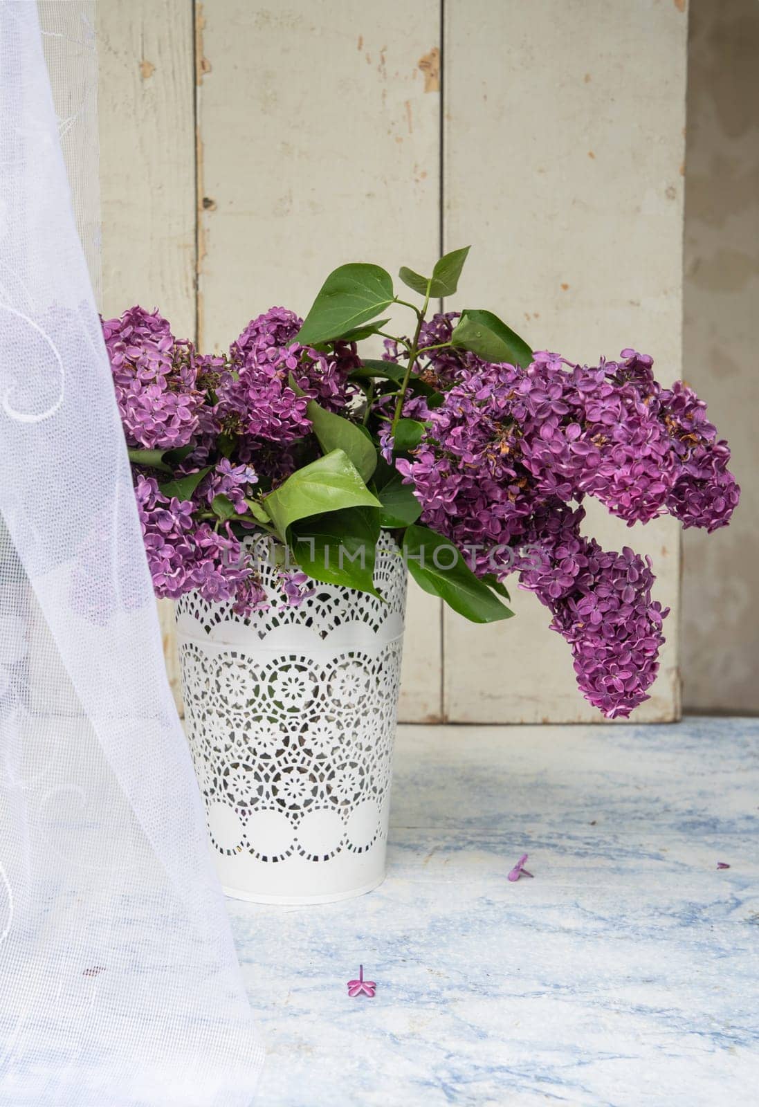 bouquet of purple lilacs in white openwork bucket on old shabby window sill with tulle curtain, romantic mood and spring freshness,comfort in the home,decoration of everyday life, High quality photo