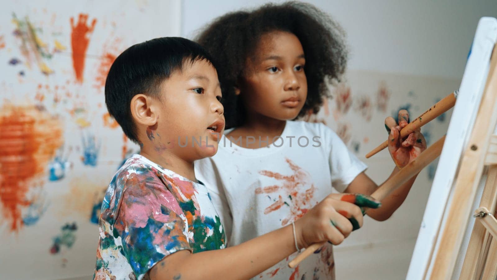 Creative african girl painted or draw canvas together with asian boy. Erudition. by biancoblue