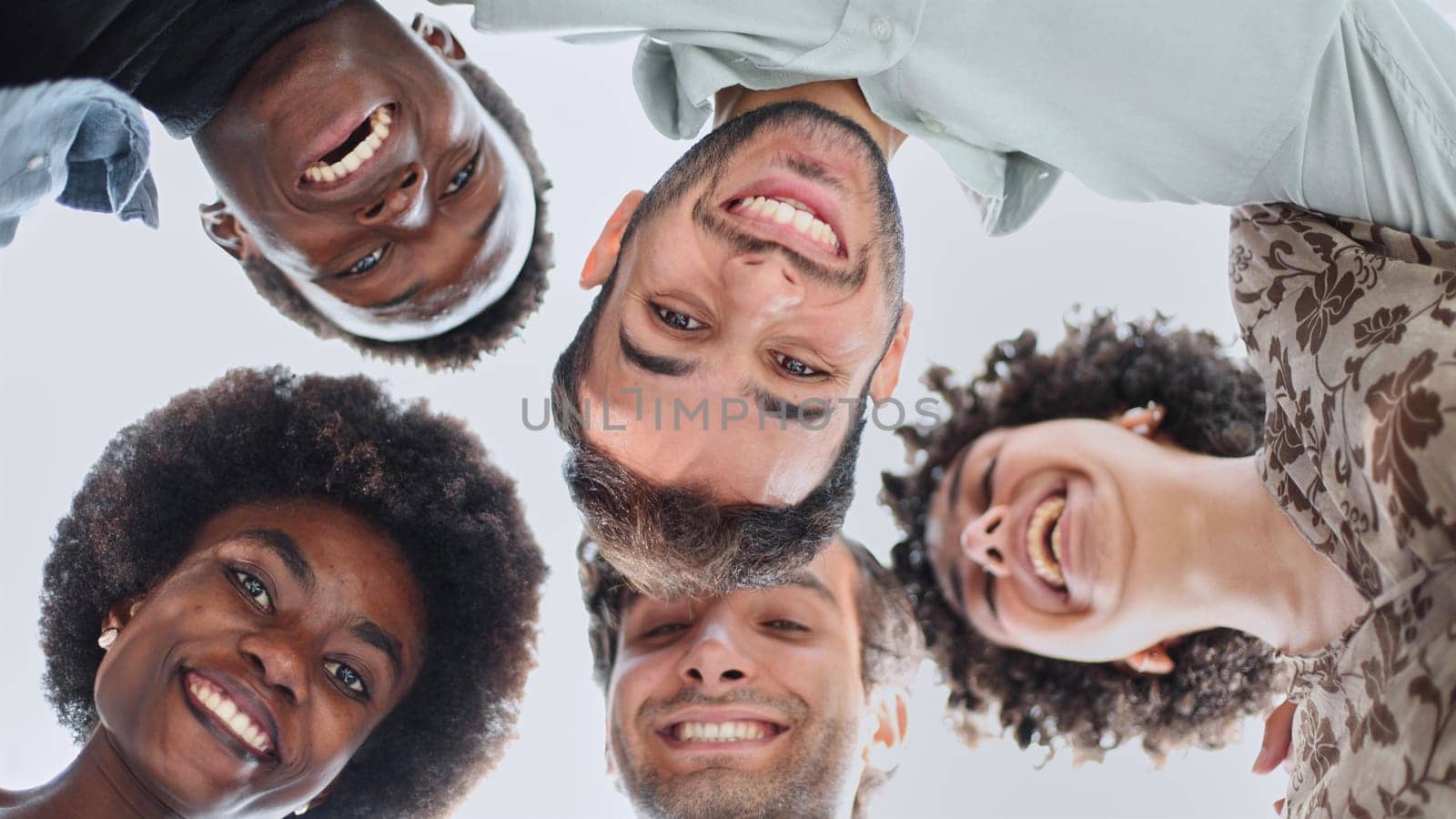 Closeup portrait, bottom view, happy faces of different team employees standing in circle, looking at camera, smiling business women and businessmen doing team building, posing for photo