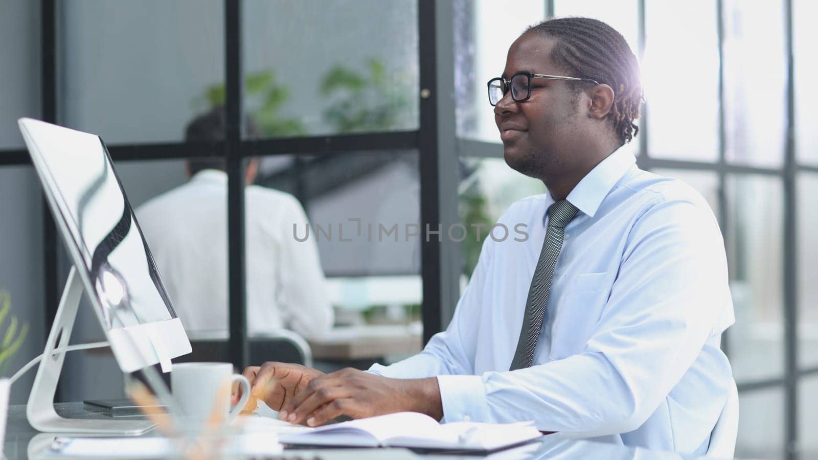 portrait of a man at his workplace at the table in front of the computer smiling.