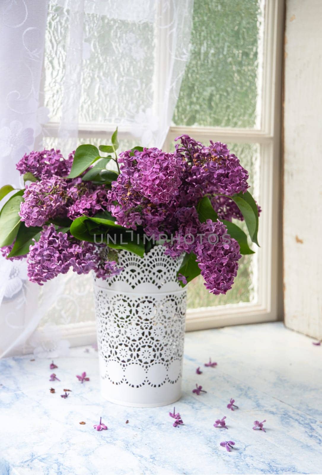 bouquet of purple lilacs in white openwork bucket on old shabby window sill with tulle curtain, romantic mood and spring freshness,comfort in the home,decoration of everyday life, High quality photo