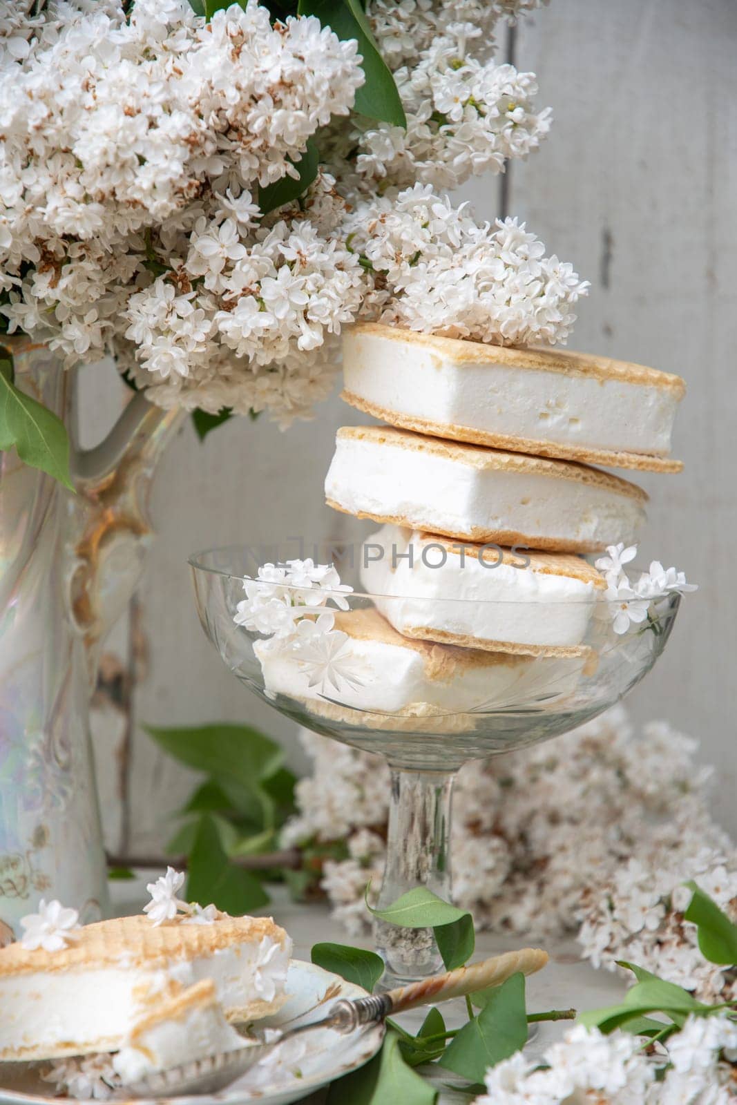 spring still life with a bouquet of white lilacs, a stack of waffle ice cream in a bowl and on a saucer, vintage ceramic dishes, high quality photo
