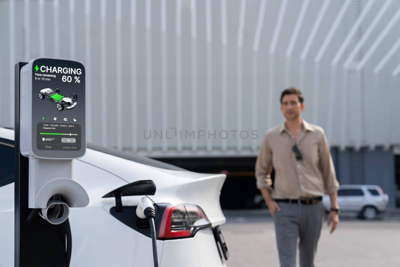 Young man put EV charger to recharge electric car's battery from charging station in city commercial parking lot. Rechargeable EV car for sustainable environmental friendly urban travel. Expedient