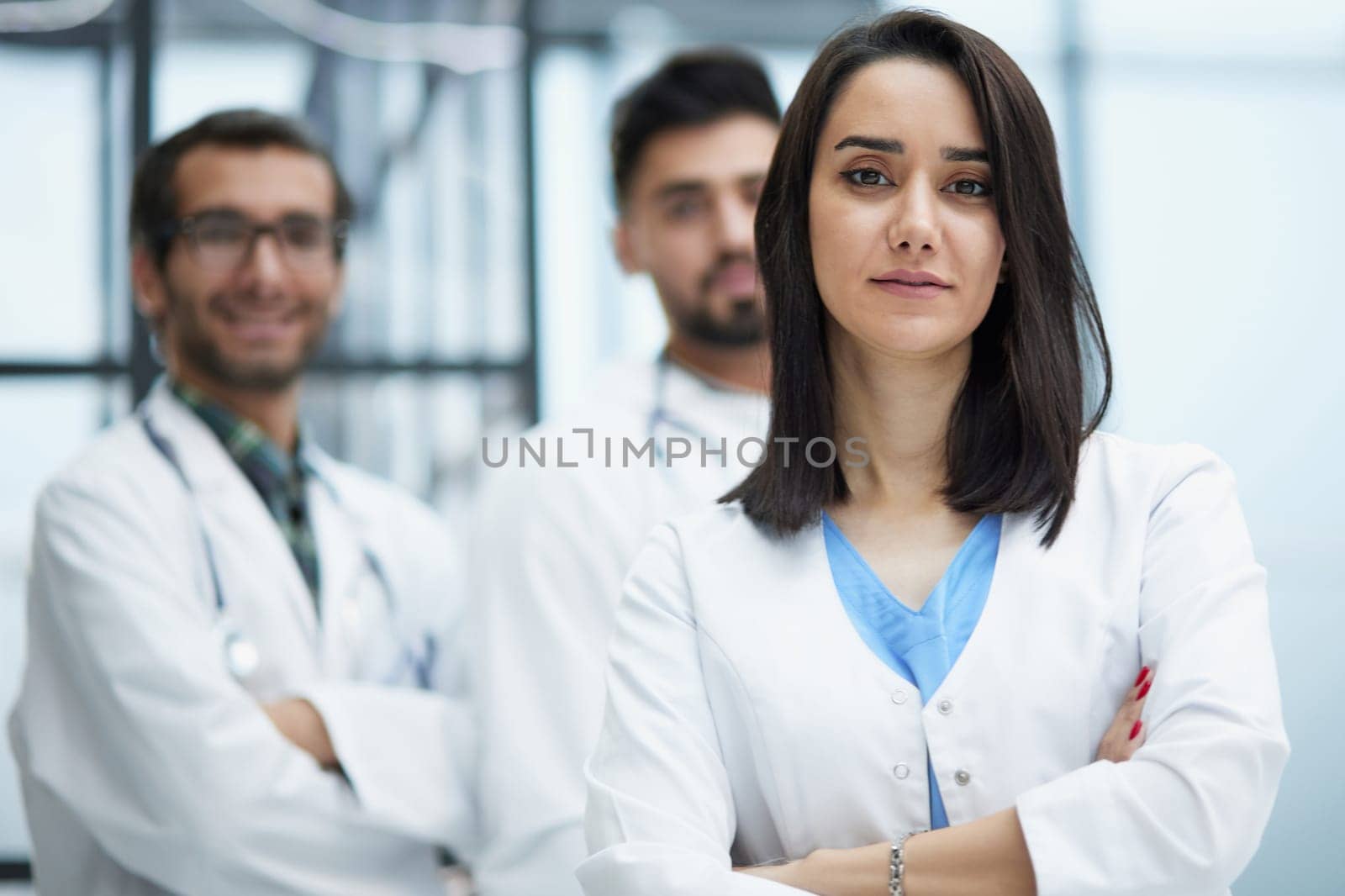 Attractive female doctor in front of the medical staff in the hospital stands with her arms crossed