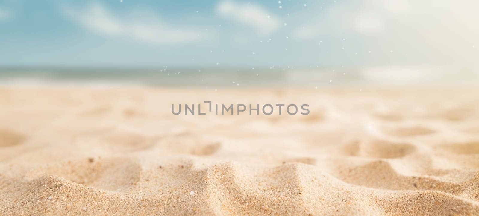 Close-up of a tranquil sandy beach with a soft-focus ocean in the background and particles glistening.