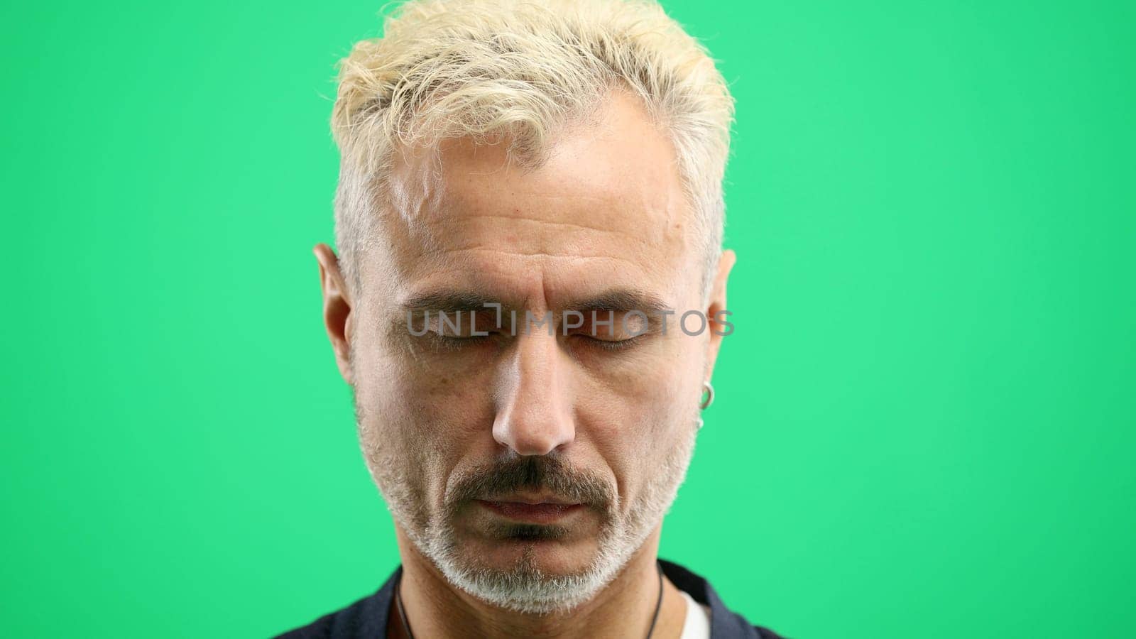 Man's face, in close-up, on a green background.