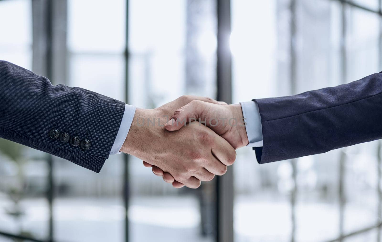 Two business people shaking hands in front of their colleagues