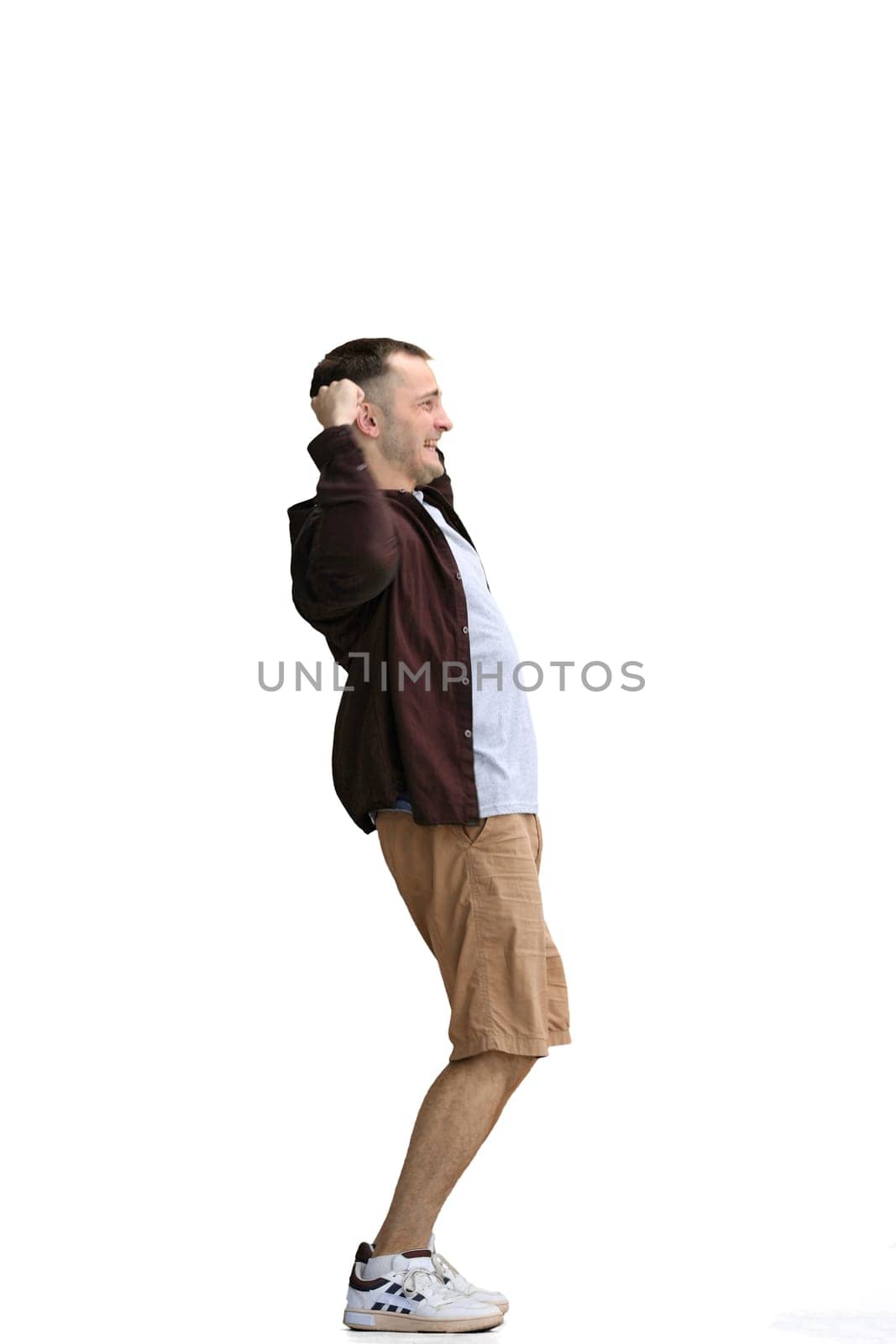 A man in a brown shirt, on a white background, in full height, raised his hands.