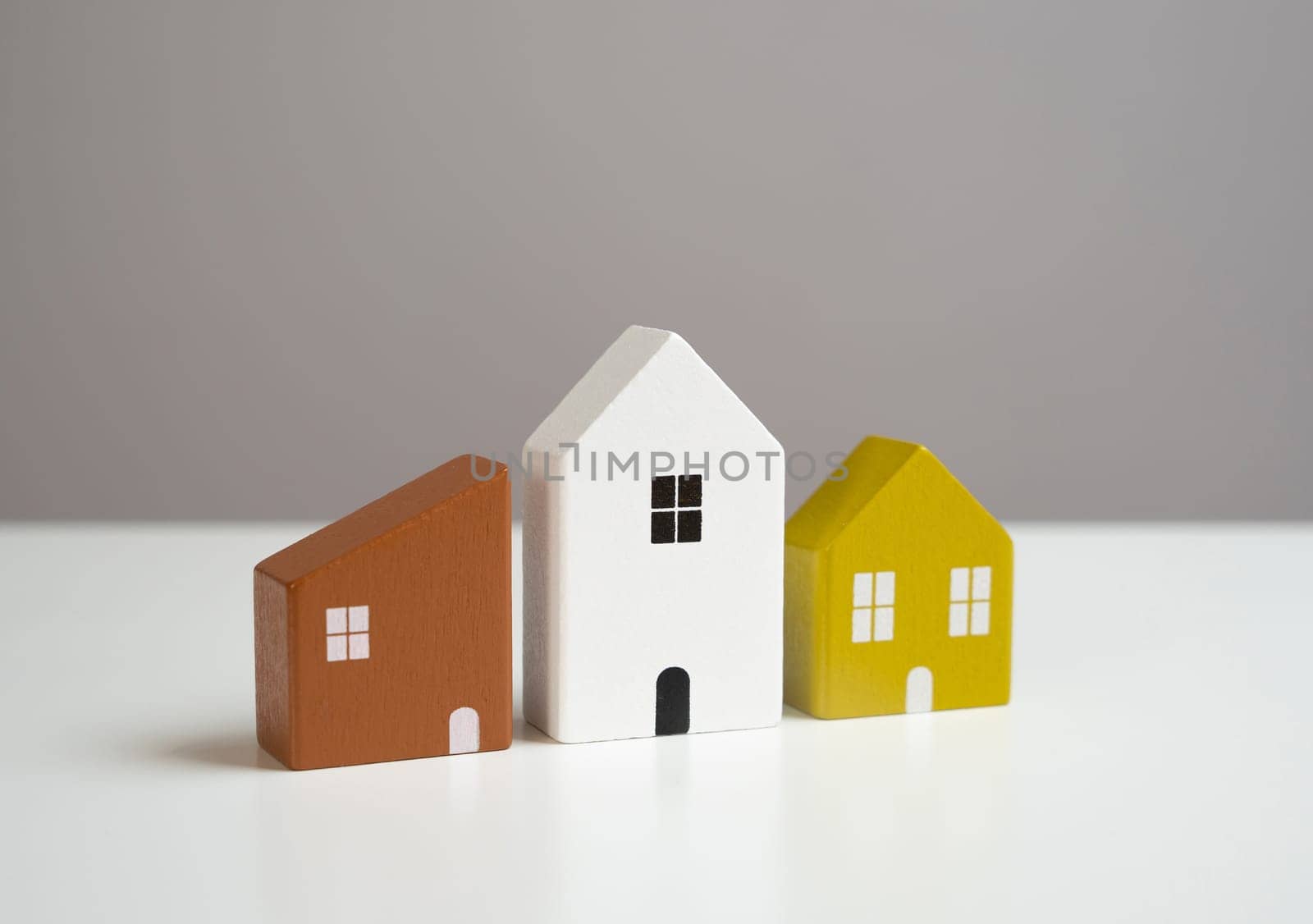 House figures standing side by side in a row. Neighborhood unity. Affordable housing options. Buying and selling.