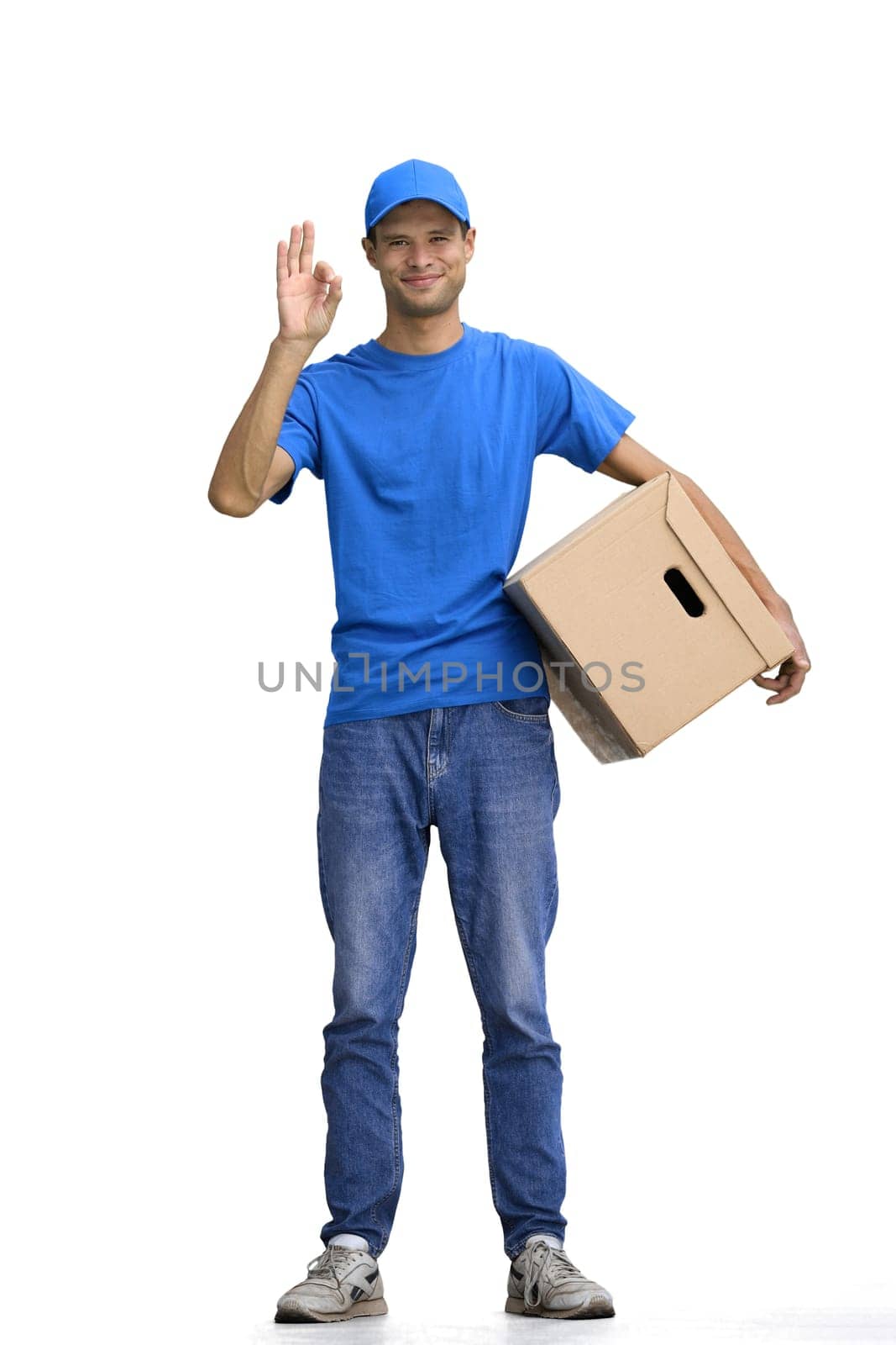 A male deliveryman, on a white background, in full height, with a box, shows the ok sign by Prosto