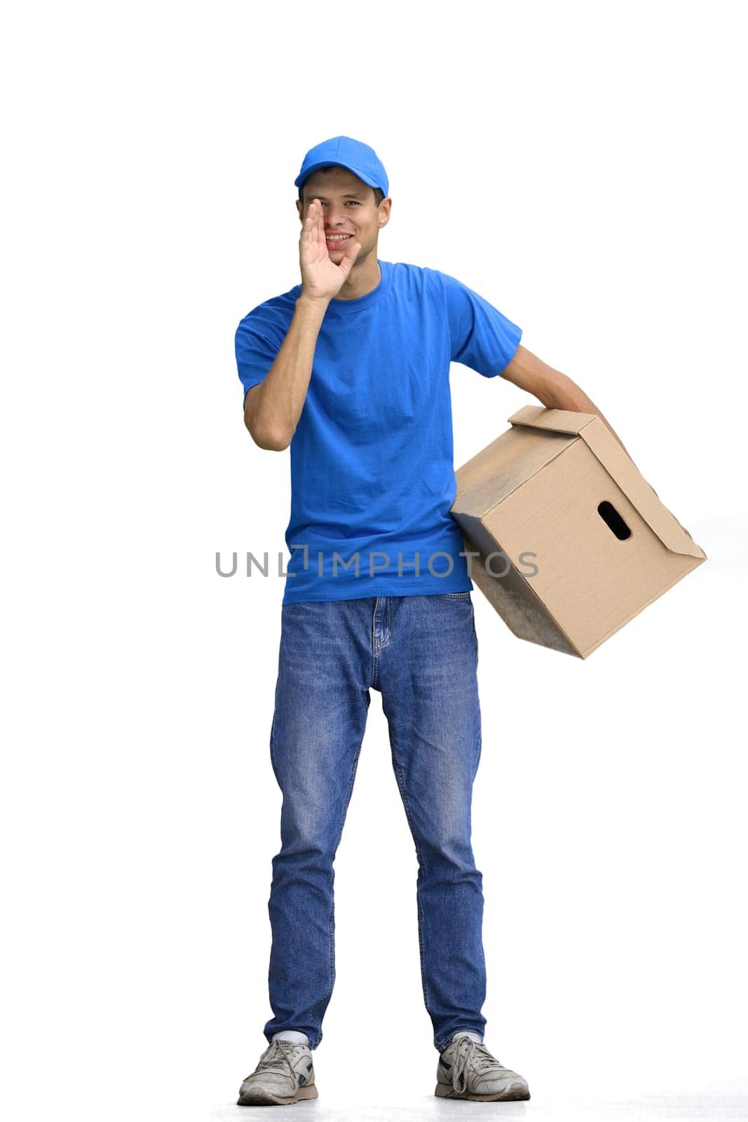 A male deliveryman, on a white background, full-length, with a box, tells a secret.