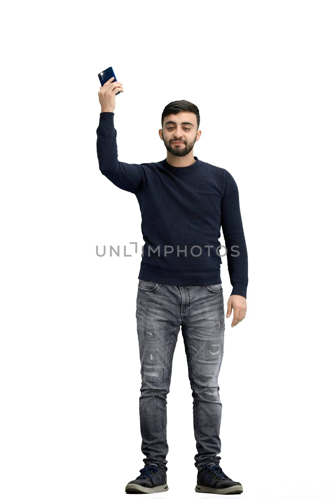 A man, full-length, on a white background, waving his phone.