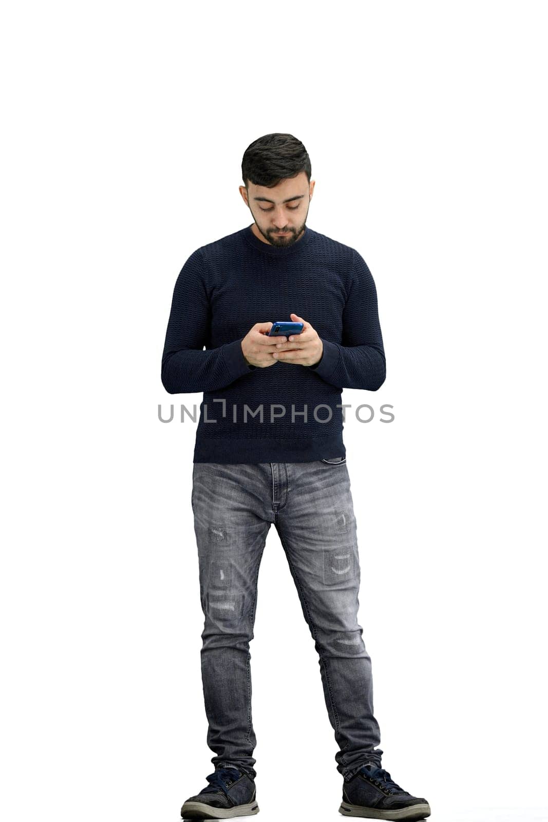 A man, full-length, on a white background, uses a phone.