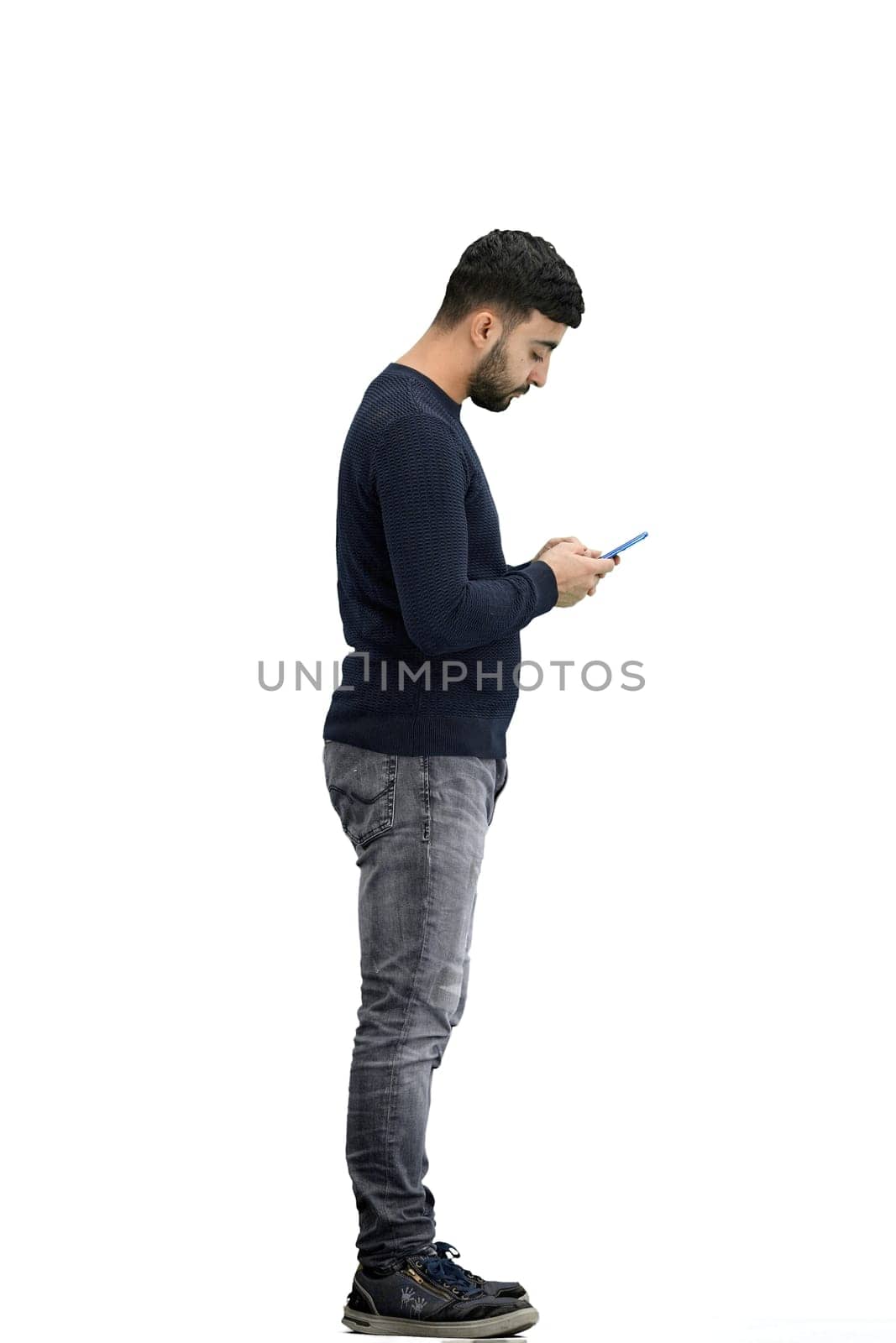 A man, full-length, on a white background, uses a phone.