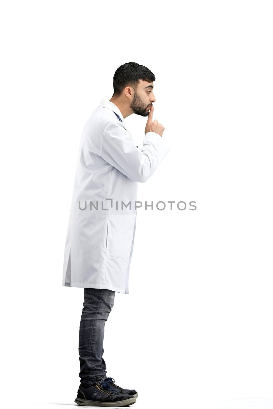 The doctor, in full height, on a white background, shows a sign of silence.