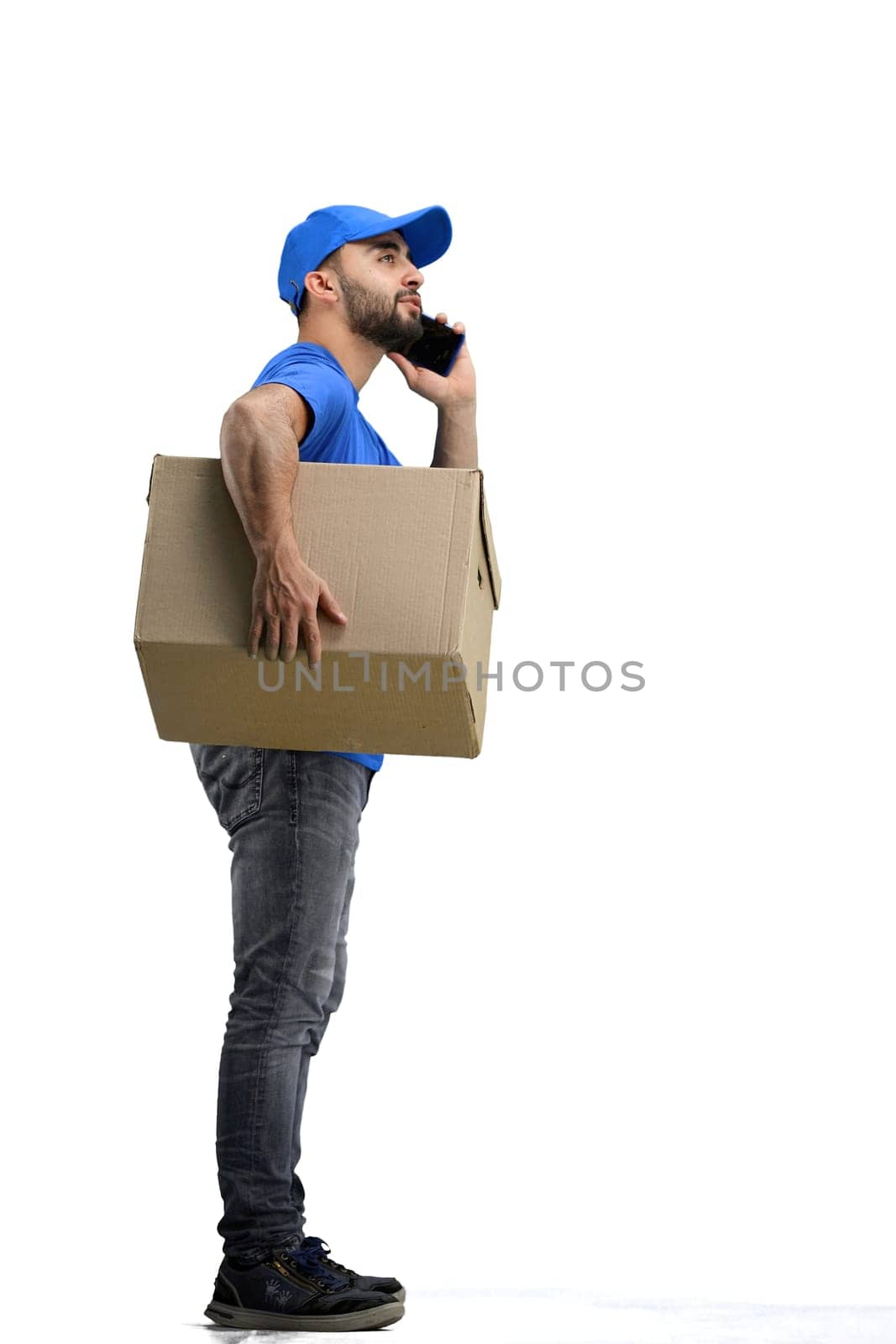 The deliveryman, in full height, on a white background, talking on the phone.