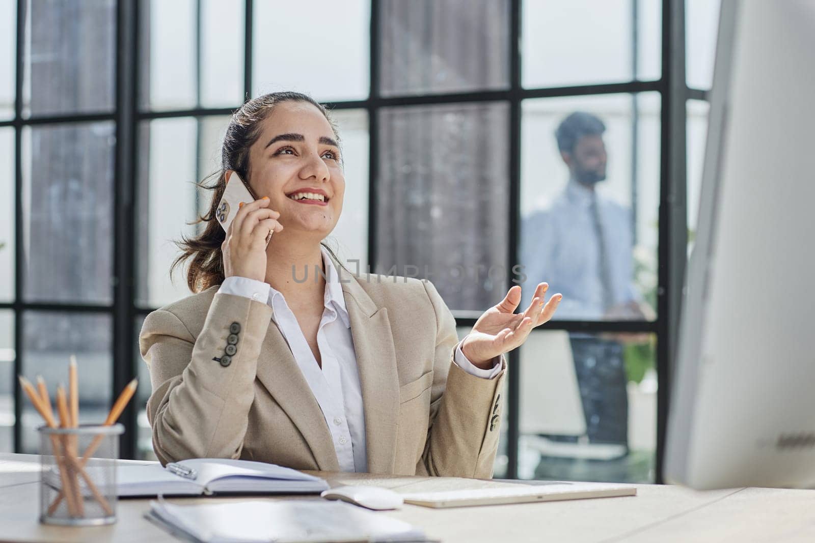 Portrait of a smiling woman talking on the phone while sitting at the table in the office