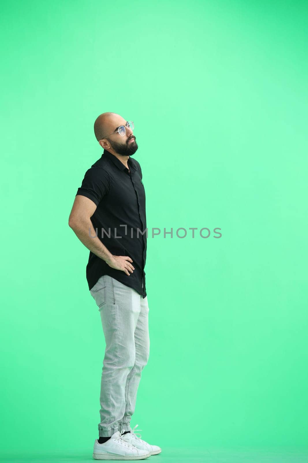 Man, on a green background, full-length, hands on hips.