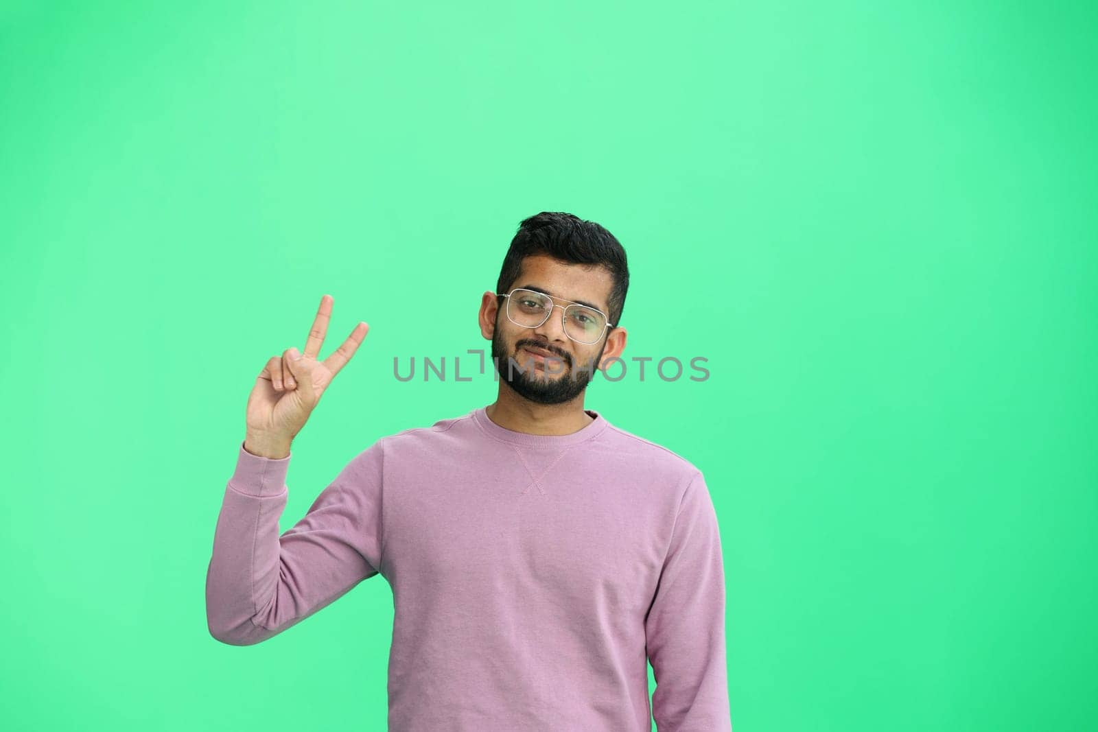 A man, on a green background, in close-up, shows a victory sign by Prosto