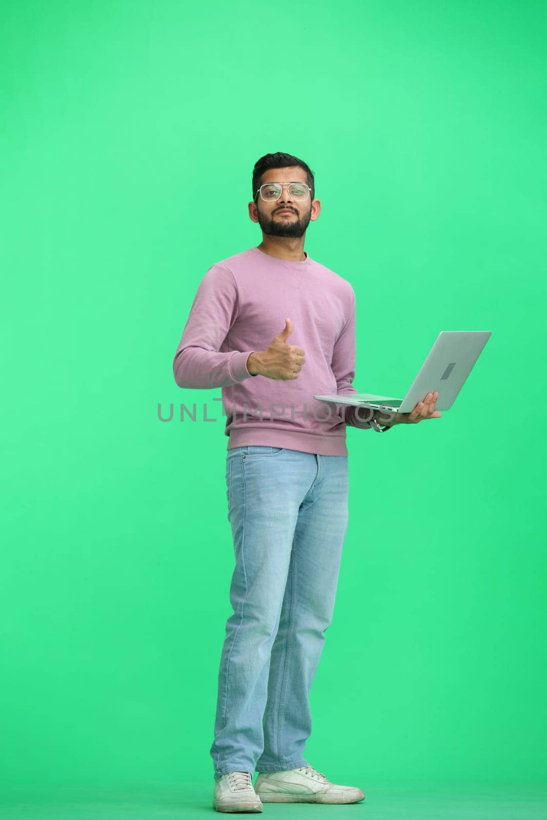 A man, on a green background, in full height, uses a laptop by Prosto