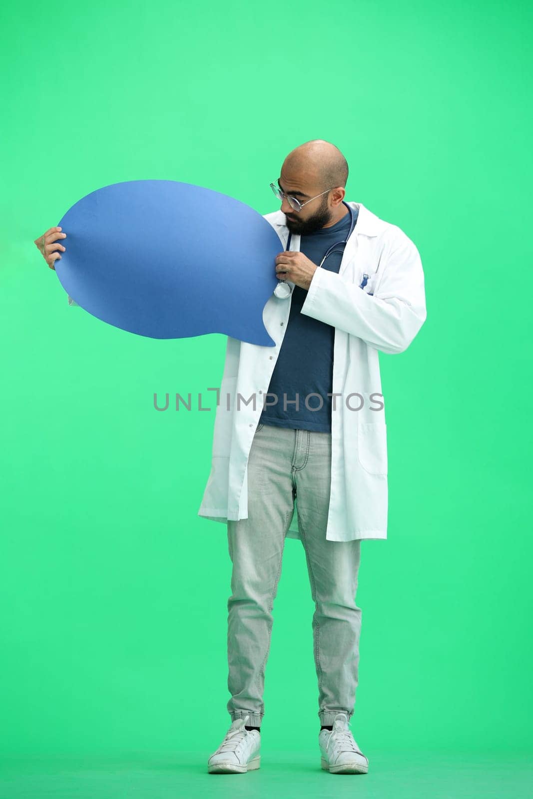 Male doctor, on a green background, full-length, with a blue comment mark.