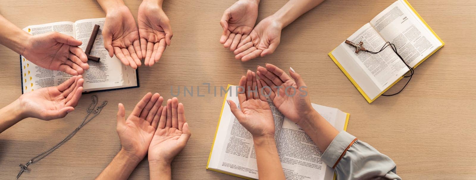 Cropped image of diversity people hand praying together at wooden church on bible book. Group of believer hold hand together faithfully. Concept of hope, religion, faith, god blessing. Burgeoning.