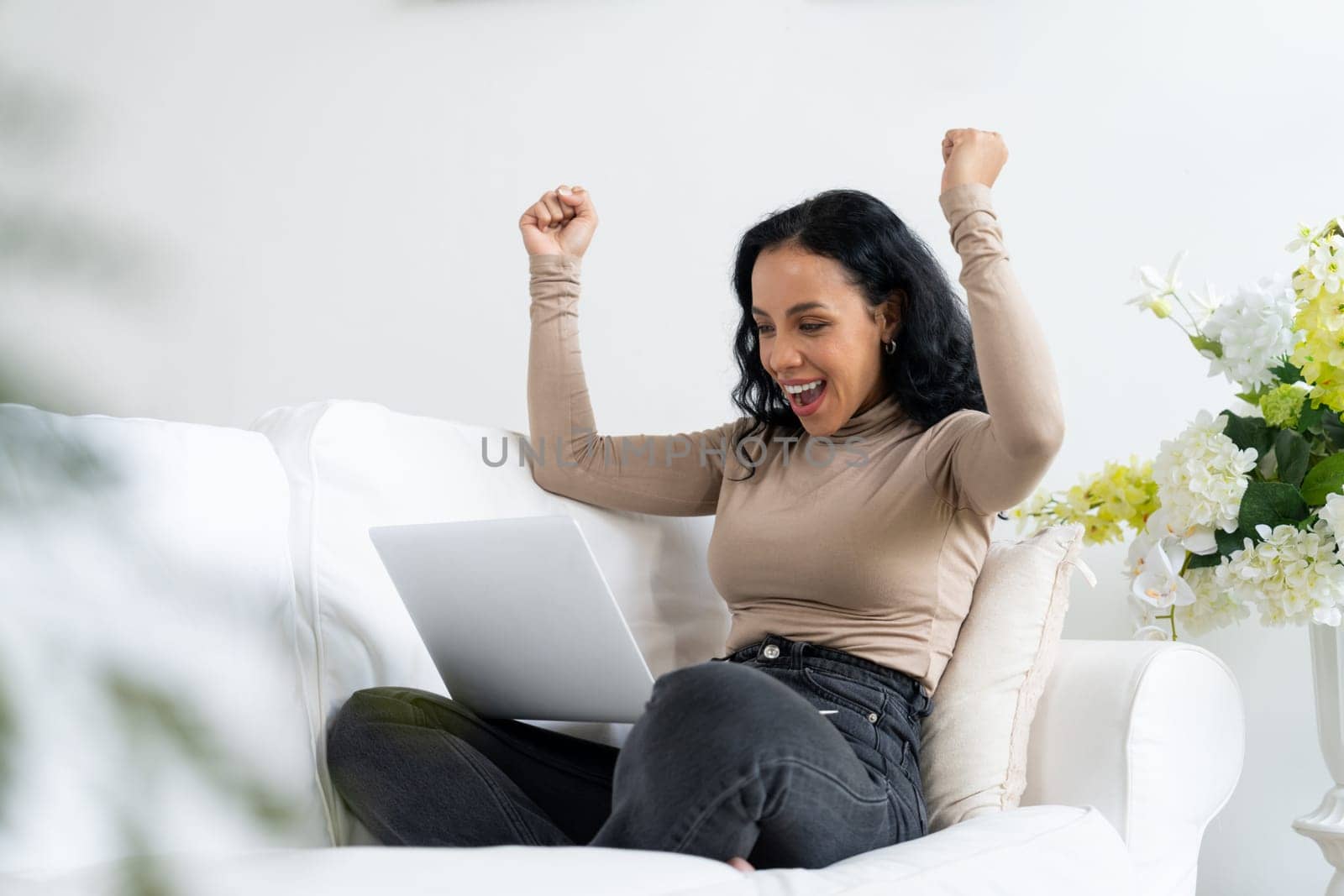 Successful African-American businesswoman feel happy at crucial work on laptop computer while sitting on sofa couch at home