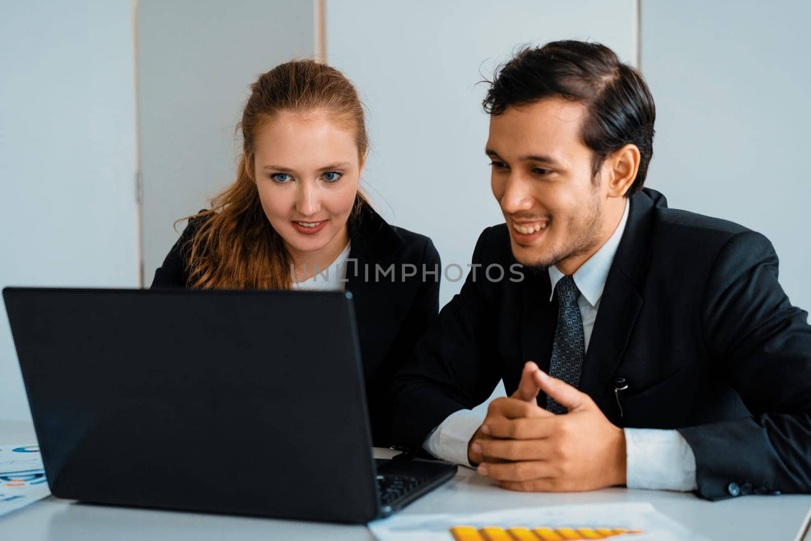 Happy businessman and businesswoman working using laptop computer at the office desk. Business teamwork concept. uds