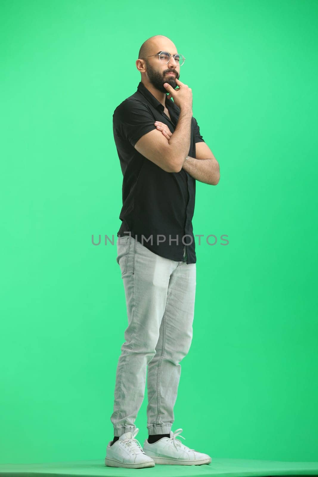A man, on a green background, in full height, thinks.