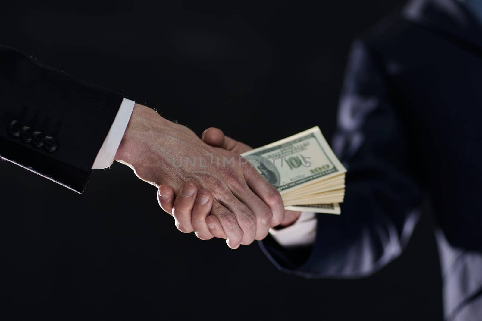 Handshake with the transfer of money on a black background by Prosto