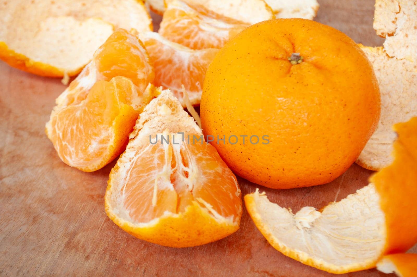 Pealed Mandarin oranges on wooden table background.