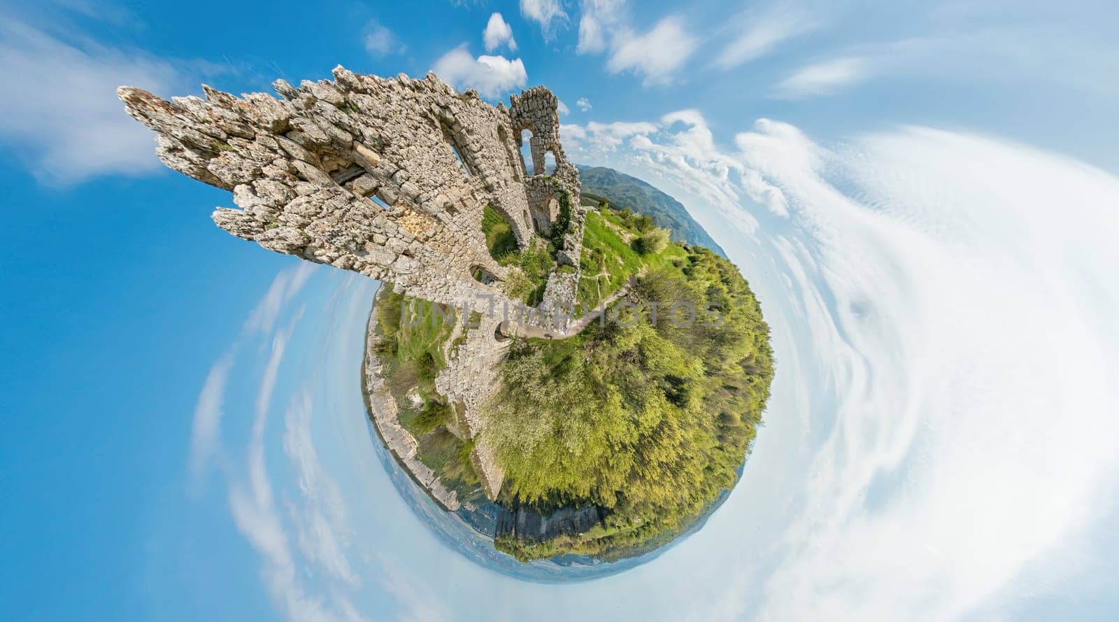 Wide panoramic view on old fortress in mountain landscape with lush green hills under clear blue sky, perfect for outdoor enthusiasts. 360 little planet panorama aerial view by panophotograph