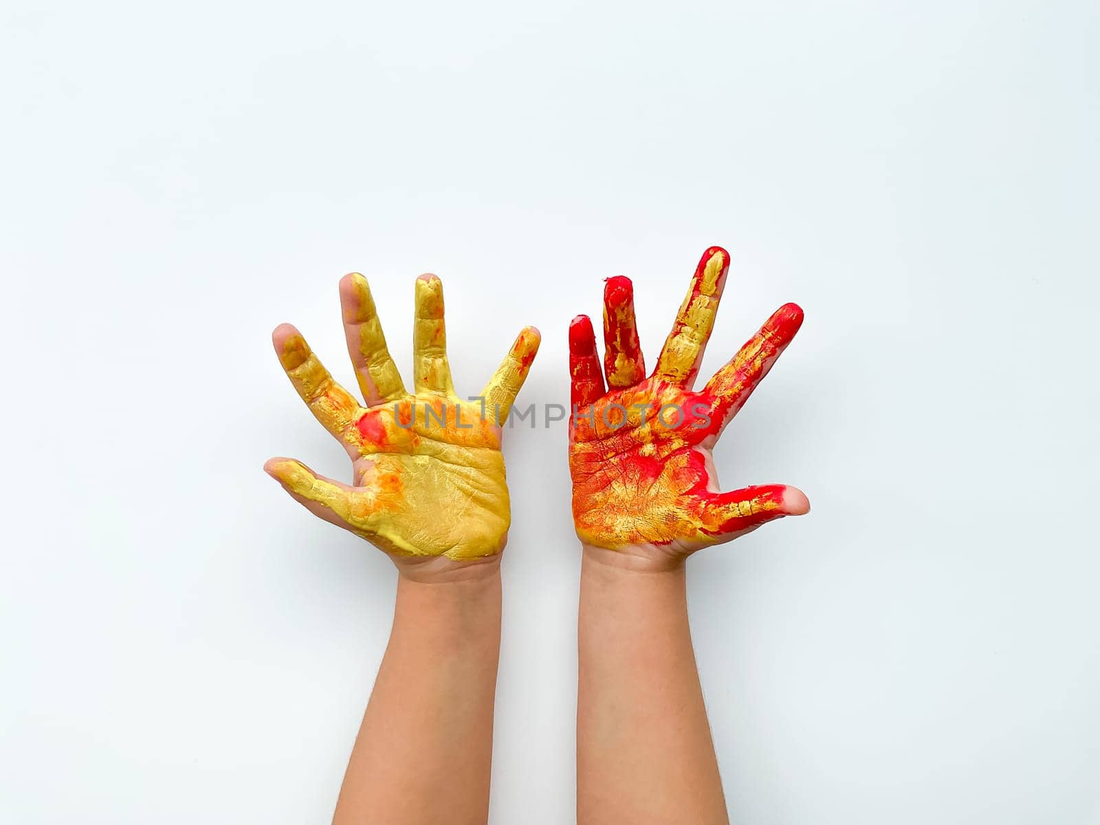 Childrens hands painted with yellow and red paint on white background. High quality photo