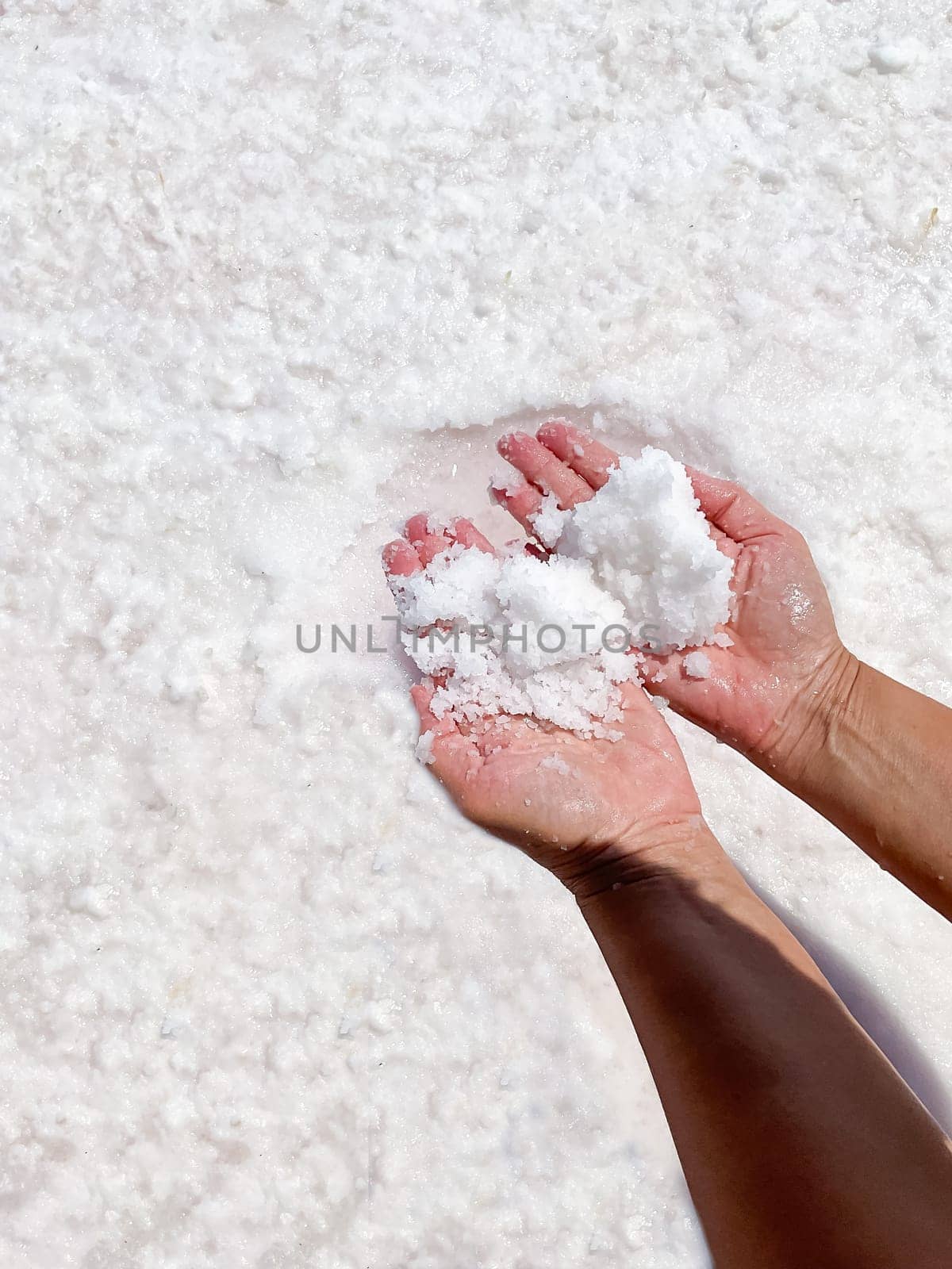 Womans hands with salt in her hands against the backdrop of salt lake. High quality photo