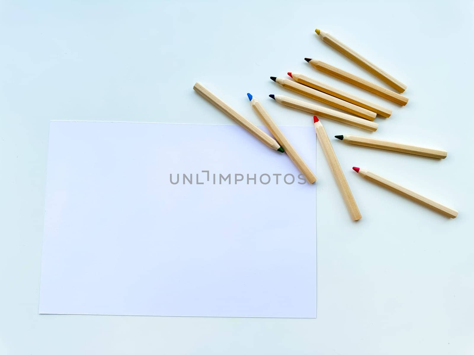 Colored pencils on table, on paper, on white background. Top view. High quality photo