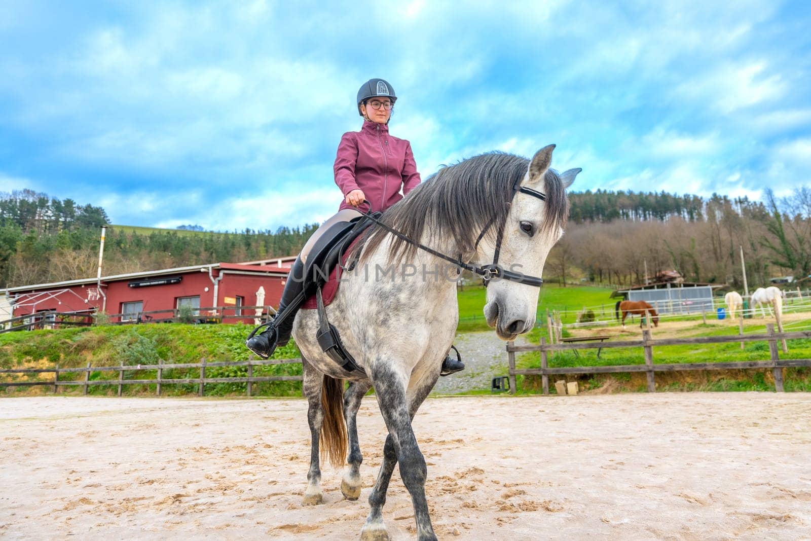 Low angle full view of a happy girl with helmet riding a horse