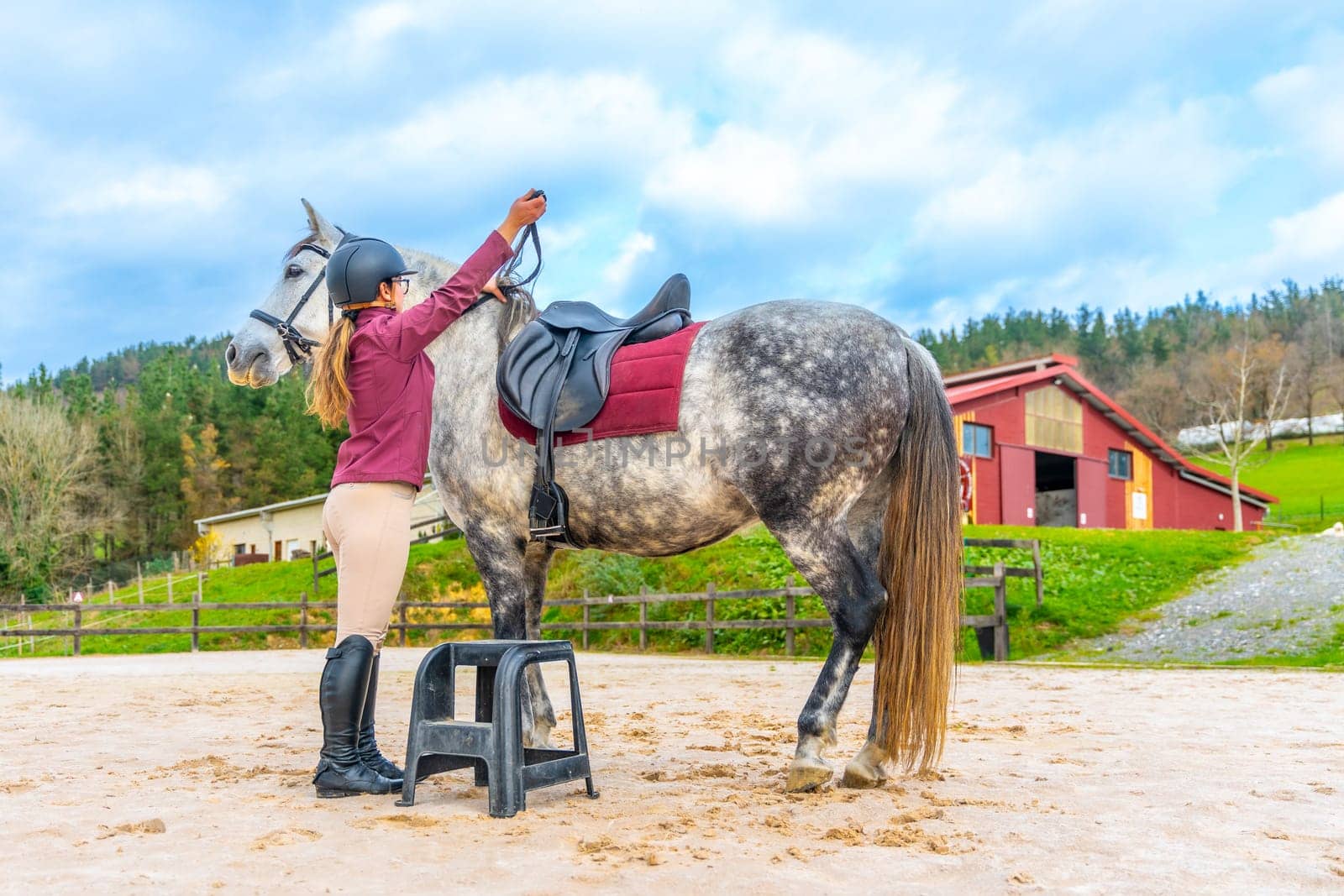 Rear view of a Woman using a step to get up and ride a horse