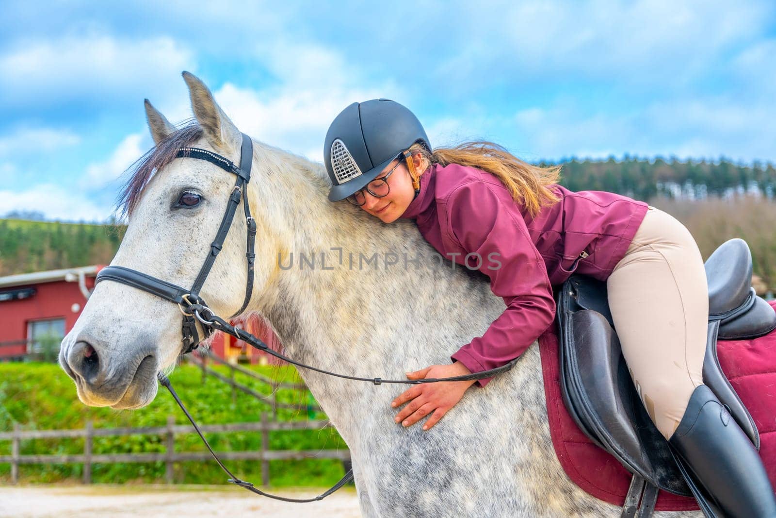 Woman embracing a horse while riding it in an equestrian center