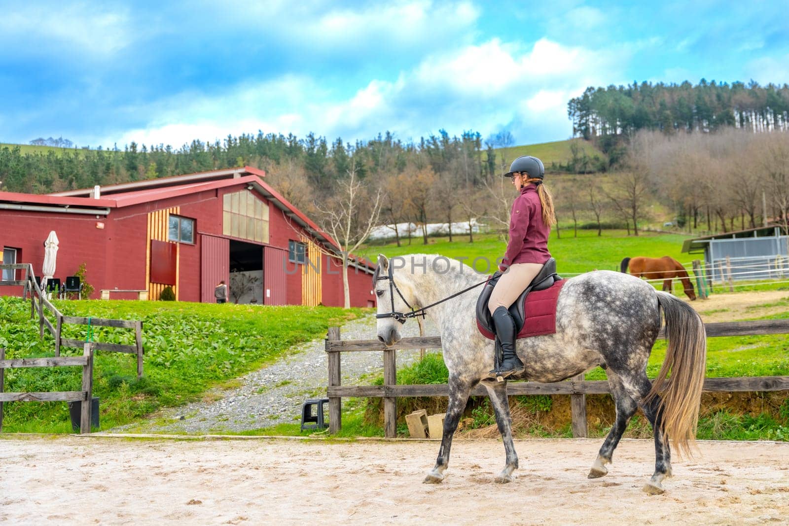 Wide view photo with copy space of a young female jockey training with her horse in an equestrian center