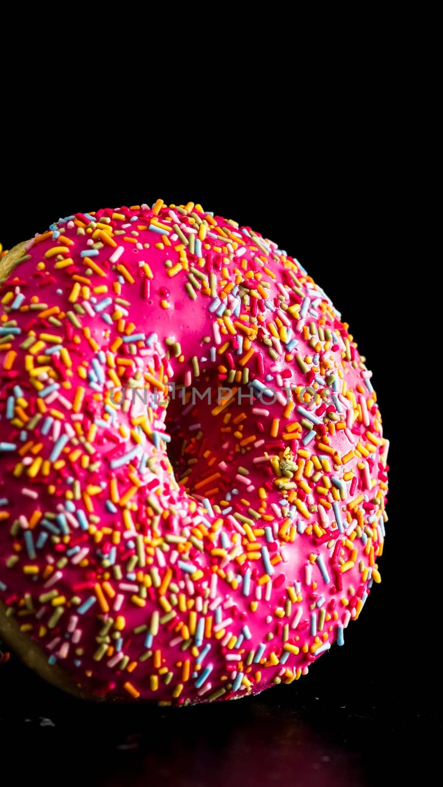 Pink glazed donut with sprinkles isolated. Close up of colorful donut.