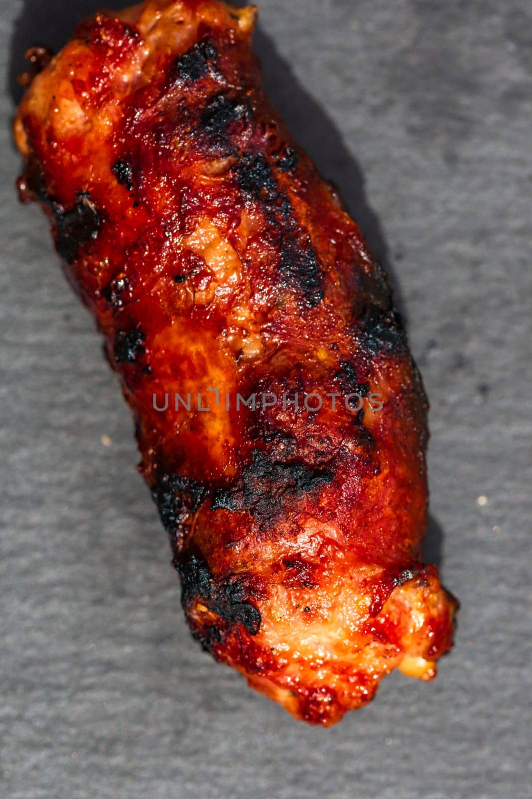 Close up of grilled sausage on small black cutting board isolated. Barbecue, grill and food concept.