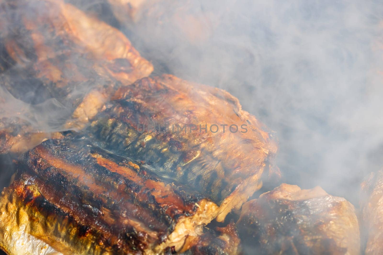 Grilled mackerel fish with smoke on a charcoal barbecue grill.  by vladispas