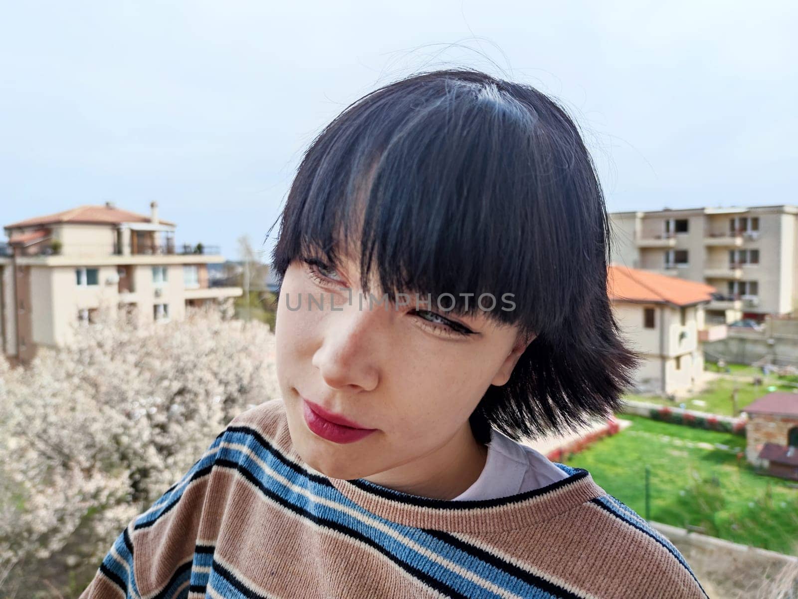 Portrait of a squinting dark-haired teenage girl on the street by Annado