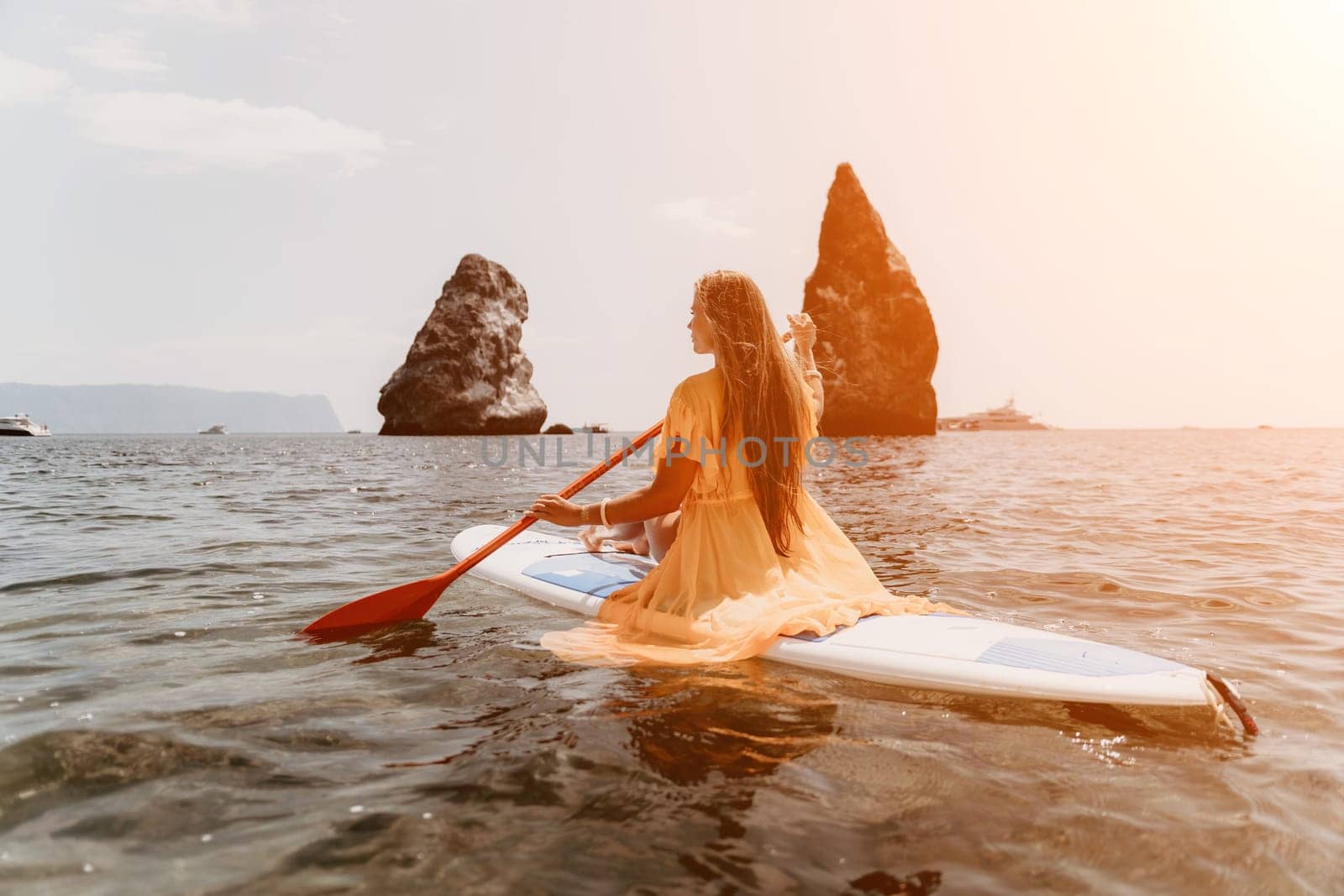 Close up shot of beautiful young caucasian woman with black hair and freckles looking at camera and smiling. Cute woman portrait in a pink bikini posing on a volcanic rock high above the sea