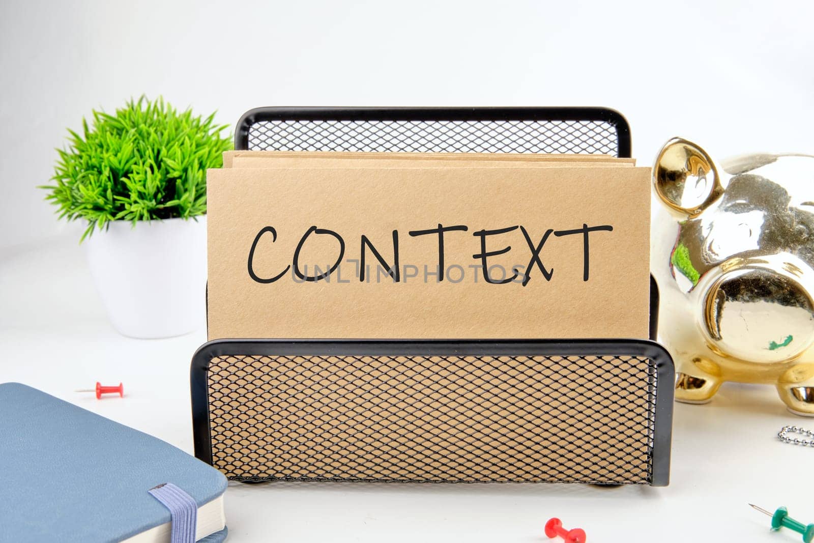 CONTEXT text on paper next to piggy bank, notepad, flower on a white background