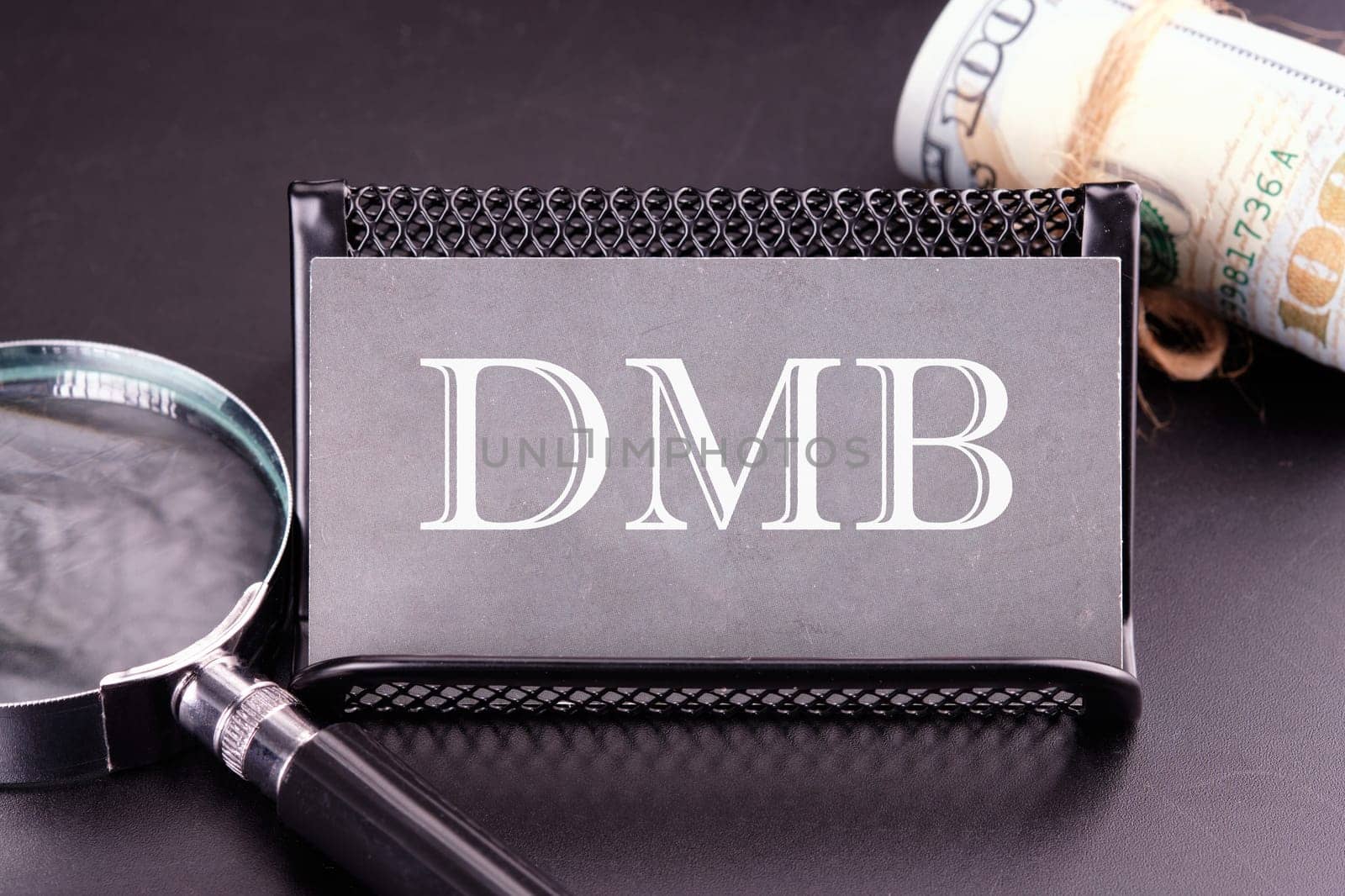 DMB text on the business card next to the money, a magnifying glass on a black background