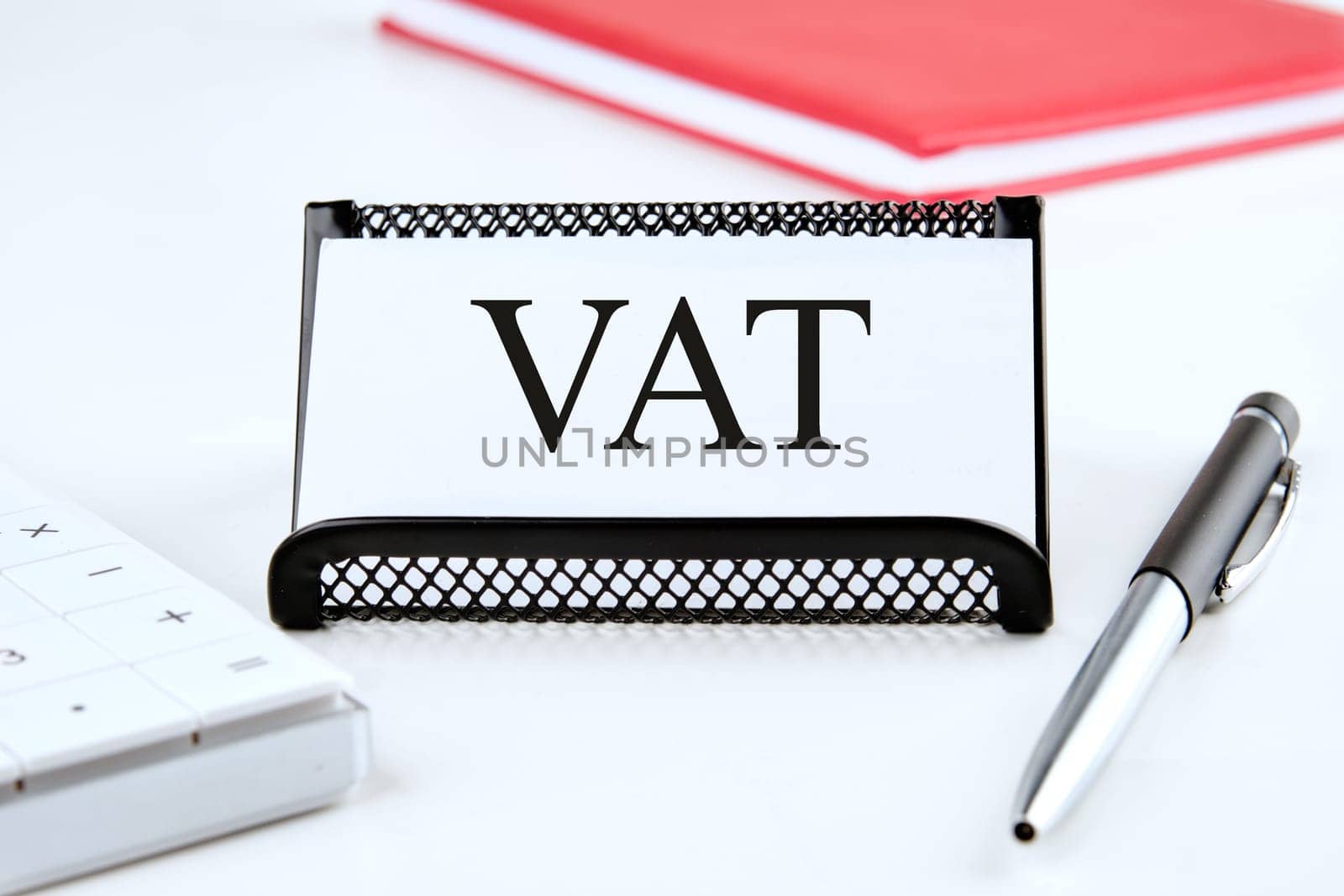 VAT the word on the business card standing on a stand next to a notepad, calculator and pen