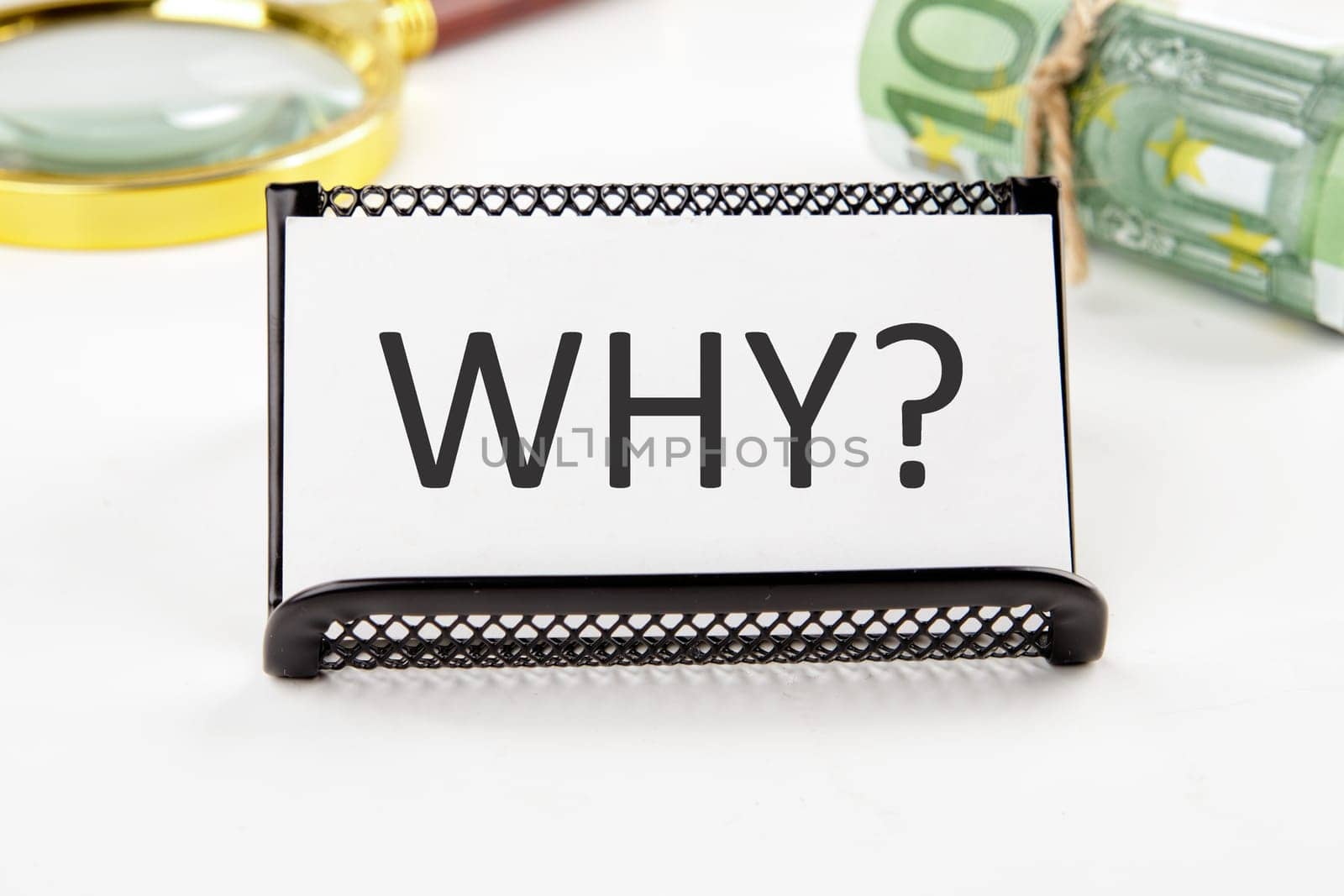 WHY the text on the business card next to the roll of money with a magnifying glass in the background is out of focus on a white background